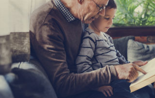 Elderly Grandparent with Dementia reading with Grandson