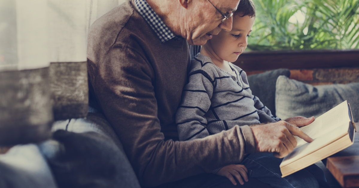 Elderly Grandparent with Dementia reading with Grandson