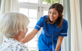 A home health care professional enjoys her job as she cares for a senior woman.