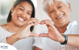 A daughter and an older mother create a heart with their hands, representing the feeling that is highlighted during National Family Caregivers Month