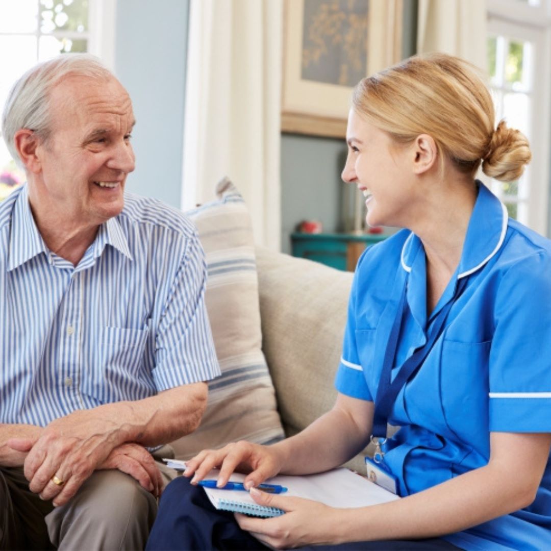Care-Management-in-West-Palm-Beach A cheerful care giver sits with and elderly patient laughing.