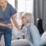 A caregiver demonstrates her caregiver skills by helping an older adult get up.